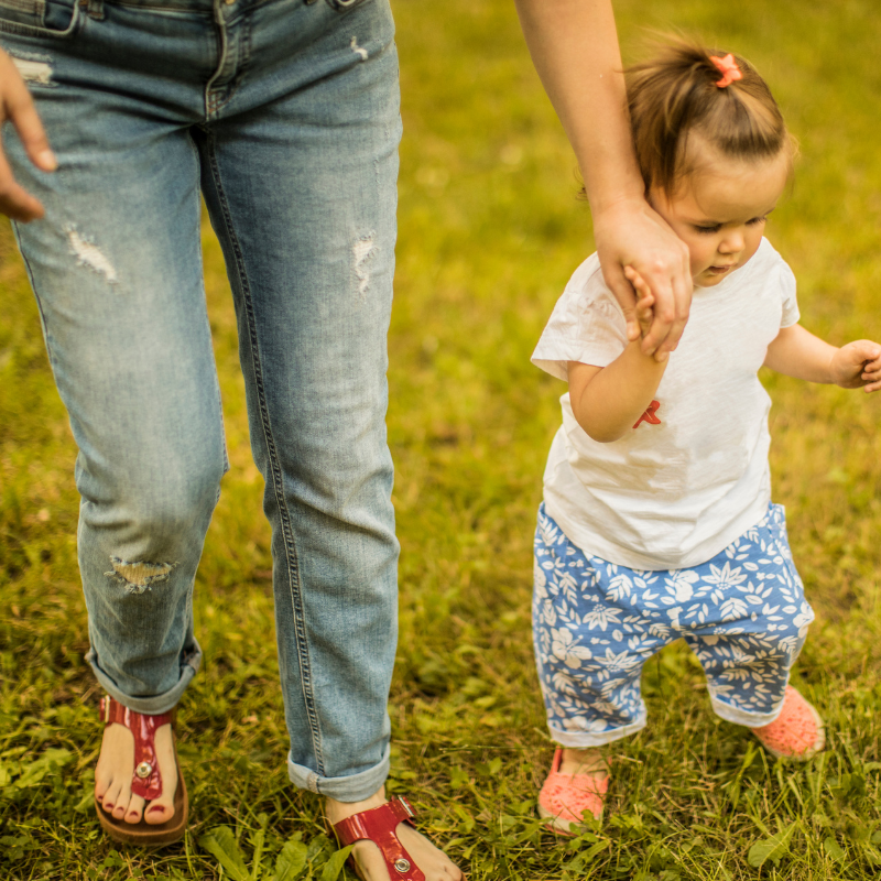 A babysitter holding a toddler's hand